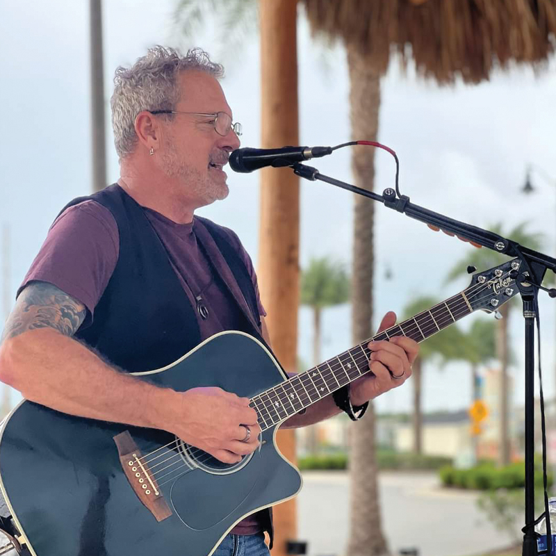 Thomas Watkins singing and playing an acoustic guitar.