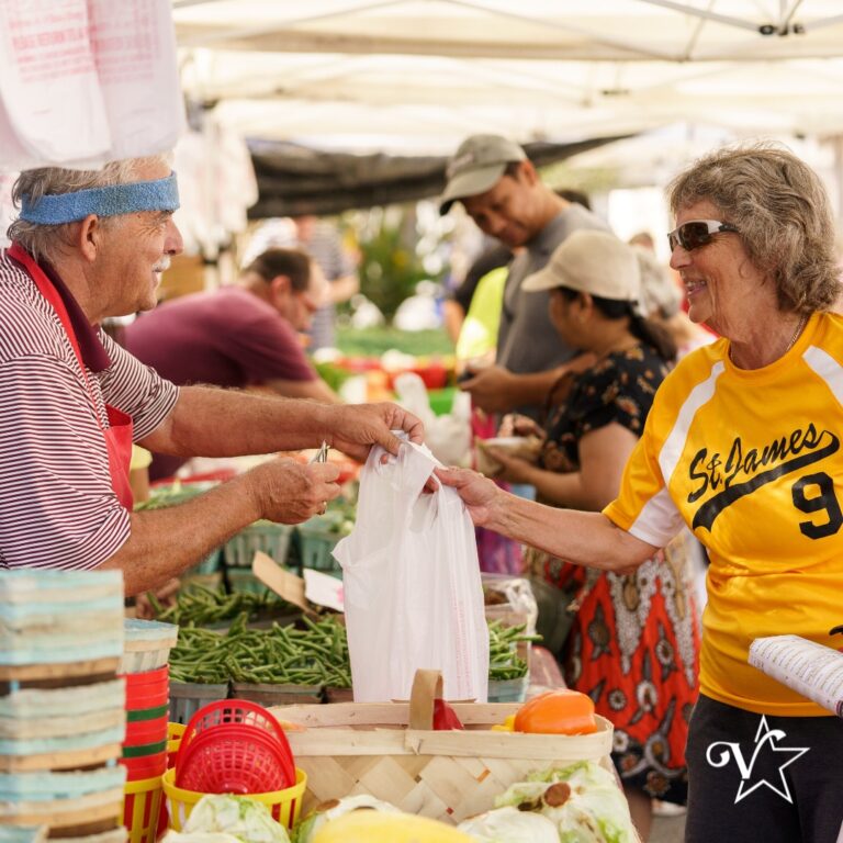 A group of people, possibly at a market, with some holding shopping bags.