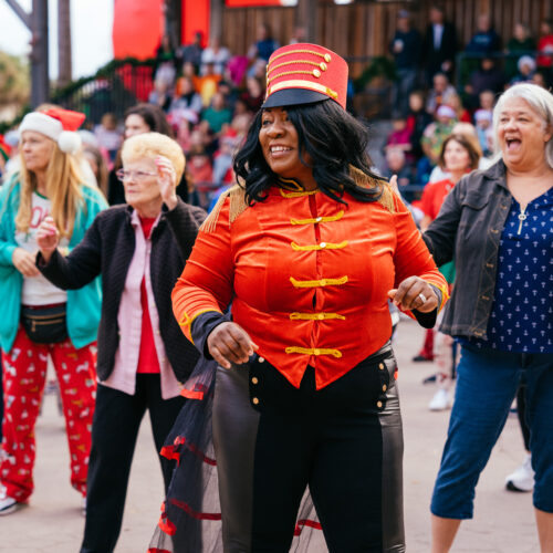 A person in an red jacket standing out in a crowd dancing.