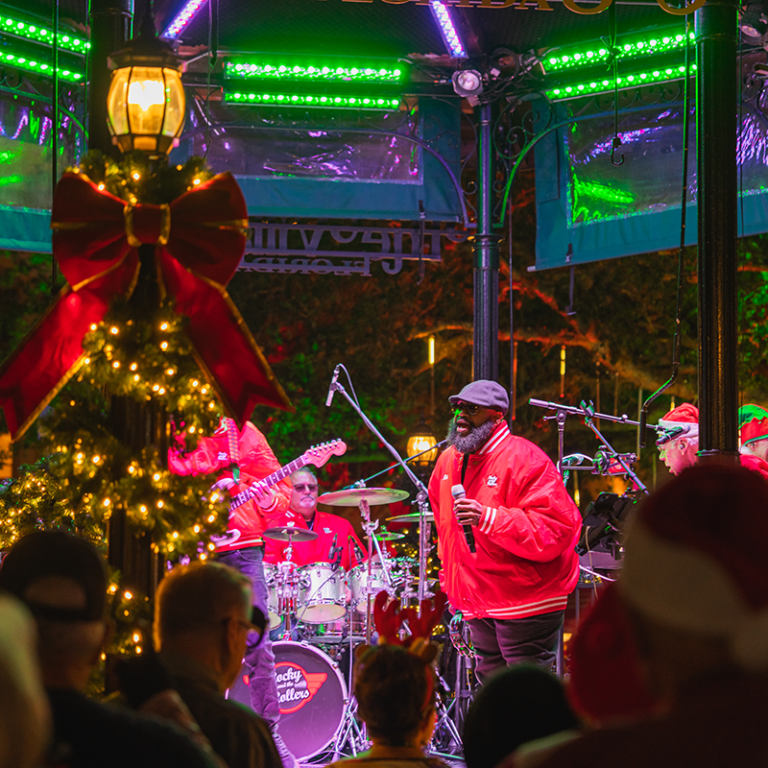 Band performing at christmas tree lighting male dressed in red performing at spanish springs