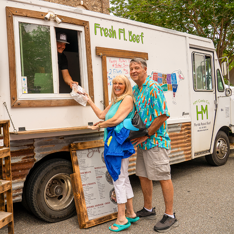 A couple purchases meat from a vendor in a food truck.