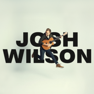 Josh Wilson holding guitar and jumping in mid air in front of text "Josh Wilson".