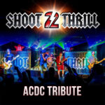 Promotional poster for “Shoot 2 Thrill,” an AC/DC tribute band. The top features a metallic logo with a glowing “2” at the center. Below, a live concert scene shows a five-piece band performing on stage with colorful lights, guitars, drums, and a singer at the front, while a crowd raises their hands in the foreground. Text at the bottom reads: “ACDC Tribute.”