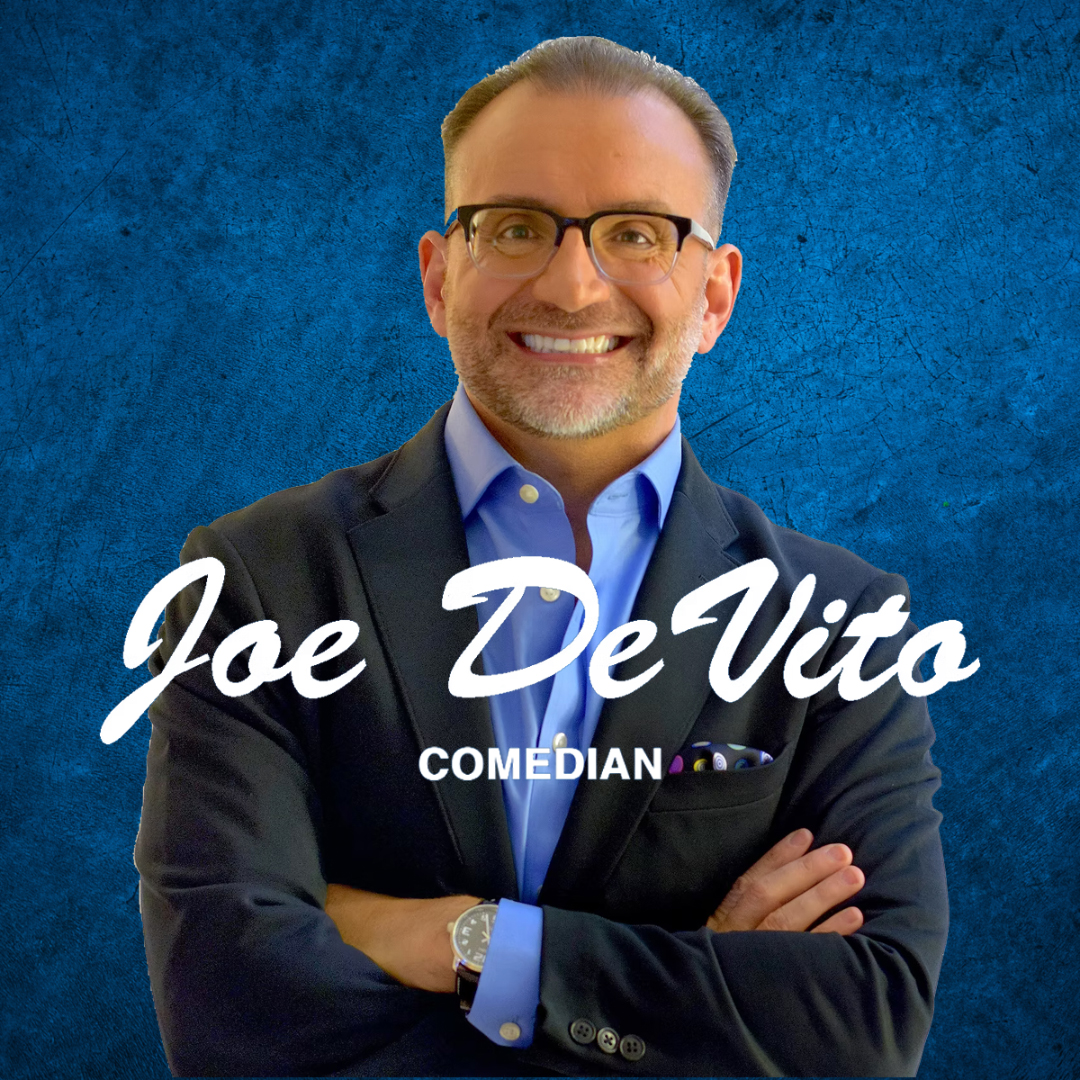 A person stands with arms crossed, wearing a dark blazer over a blue dress shirt with a pocket square, against a textured blue background. Large white script text across the center reads “Joe DeVito,” with smaller uppercase text below reading “Comedian.”