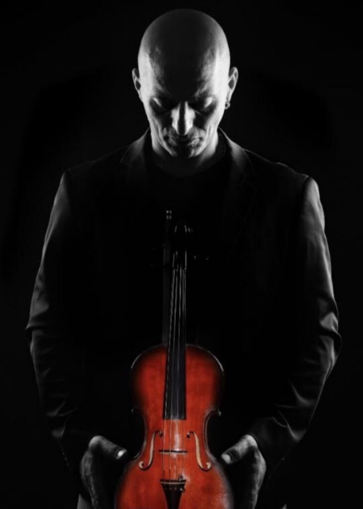 Gennaro Desiderio, pictured in black and white, looks down at his violin, pictured in color.