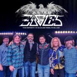 Photo of 6 group members on a stage with a string of lights behind them. The title "Alter Eagles - The Definitive Eagles Tribute Band" is written at the top.