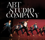 Promotional graphic reading “ABT Studio Company,” featuring multiple dancers captured midair in coordinated movement on a stage, with dramatic lighting and a red backdrop behind them.