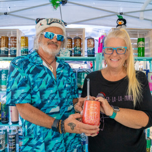 A man and woman are holding a cup they created, the man wearing a Philadelphia Eagles santa hat.