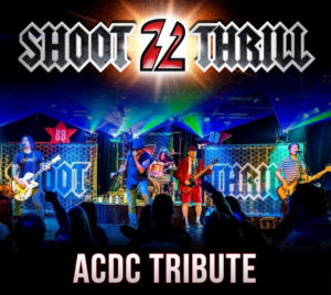 Promotional poster for “Shoot 2 Thrill,” an AC/DC tribute band. The top features a metallic logo with a glowing “2” at the center. Below, a live concert scene shows a five-piece band performing on stage with colorful lights, guitars, drums, and a singer at the front, while a crowd raises their hands in the foreground. Text at the bottom reads: “ACDC Tribute.”