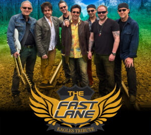 Promotional poster for The Fast Lane - Eagles Tribute. 7 band members are pictured standing on rail road tracks with a green tinted sky behind them. The title is below them overlaying an orange symbol that looks like wings.