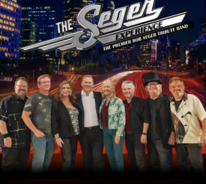 Promotional poster for The Seger Experience. The band members are pictured in front of a city street at night. City buildings are illuminated behind them. Above them it reads "The Seger Experience, The Premier Bob Seger Tribute Band."