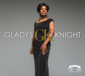 A promotional image with the name “Gladys Knight” displayed across the center, with large gold initials “GK” displayed in between the two names. A performer stands in the center wearing a textured, floor-length black gown and jewelry, posed against a smooth gray gradient background. A small “Get Off The Bus Concerts - Great Concerts for Great Causes” logo appears in the lower right corner.