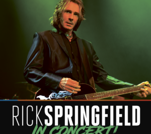 Rick Springfield performing live on stage with guitar under green lighting, with bold text below that reads “Rick Springfield In Concert.”