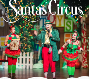 Santa Claus and festive circus performers on a decorated holiday stage with twinkling lights and oversized candy props, under the title “Santa’s Circus.”