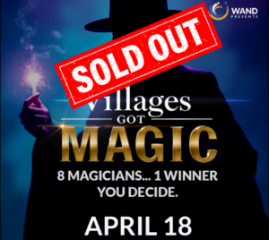 Promotional poster for "Villages Got Magic" showing a silhouetted magician in a top hat, holding a sparkling flame, against a blue background. White text reads "Villages Got Magic" with the word "Magic" in bold, gold letters and smaller text below reading: "8 magicians… 1 winner. You decide." A red "Sold Out" stamp overlays the top of the image. Event date shown as April 18, with the Wand Presents logo in the upper right.